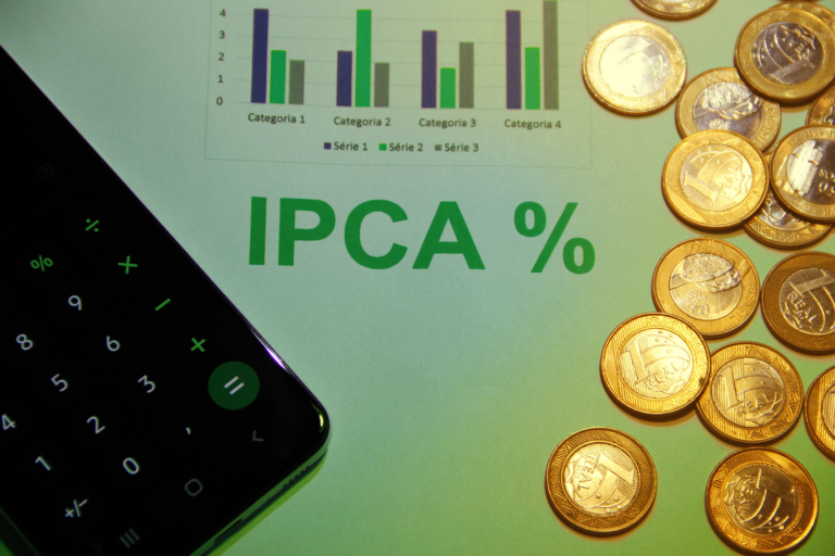 Gráficos de IPCA em uma mesa ao lado de uma calculadora e algumas moedas