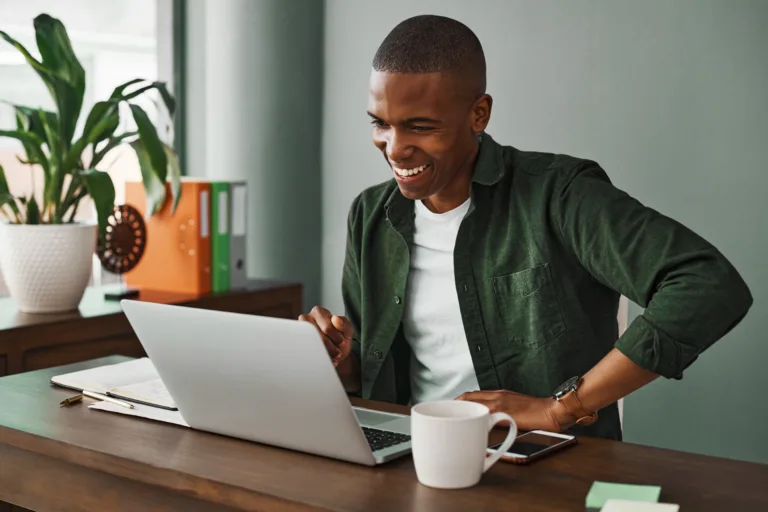 jovem sorrindo olhando para notebook referente às possibilidades de se investir com salário de jovem aprendiz