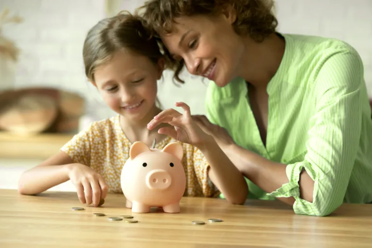 mãe com filha colocando moeda em cofre de porquinho de mesada educativa